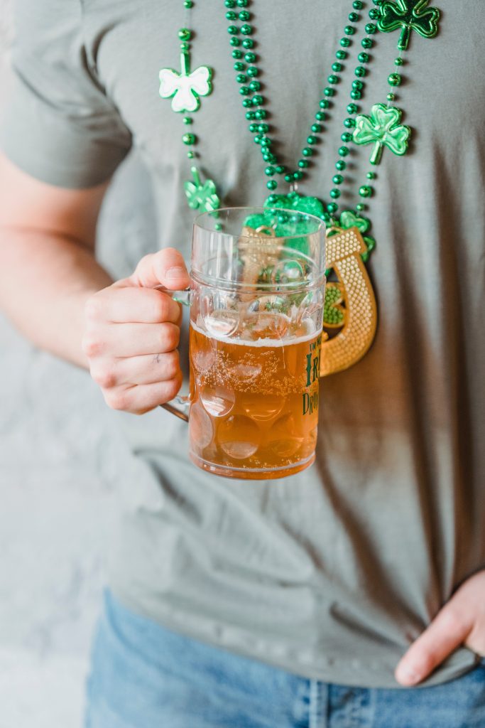 person holding beer wearing 4 leaf clover necklace